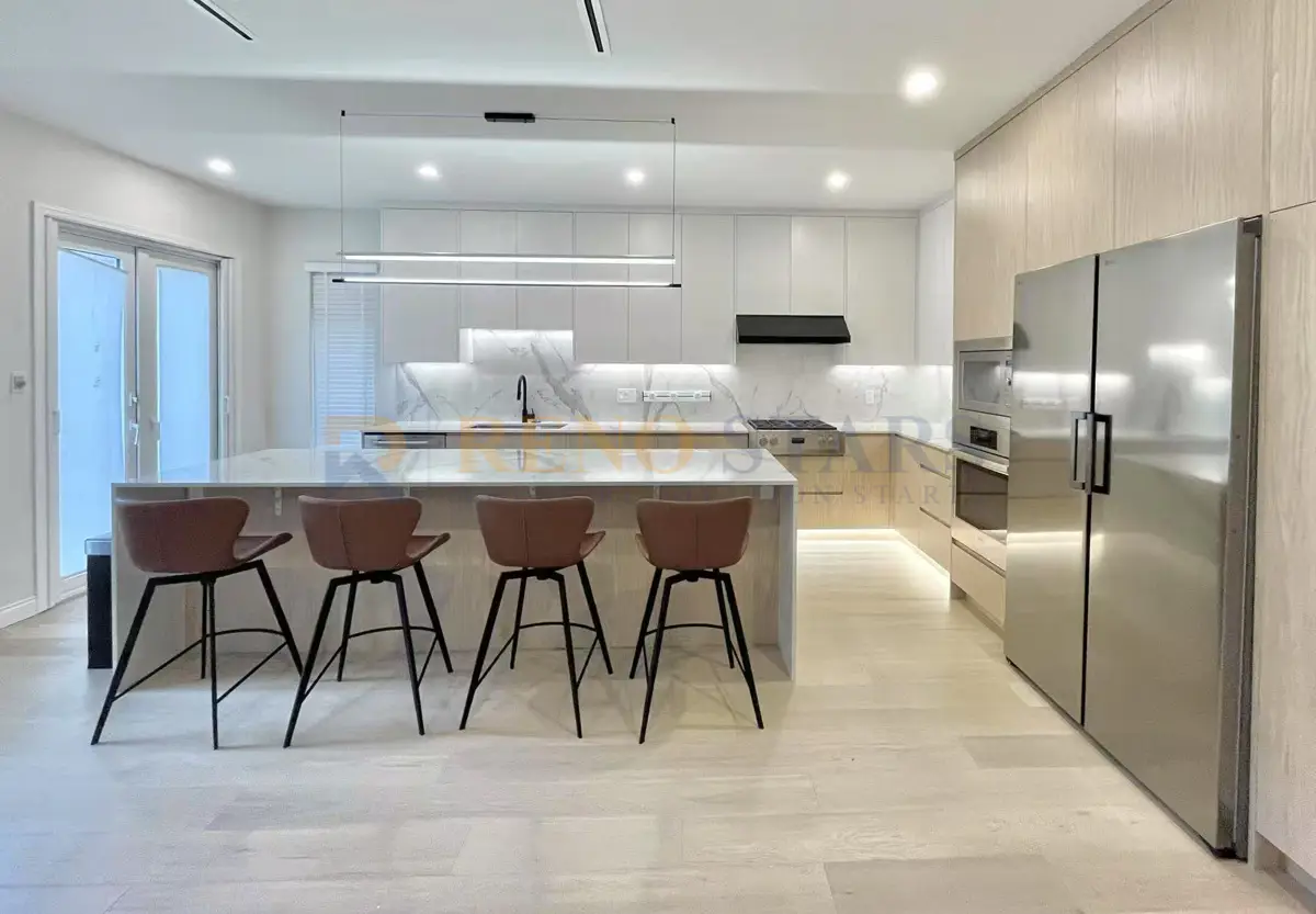 White shaker kitchen cabinets with black hardware, dark quartz countertop, and undermount sink in a Burnaby home