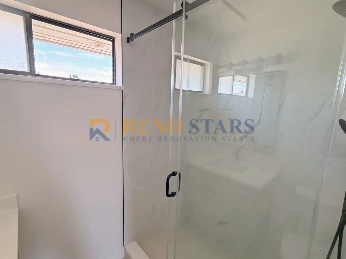 Modern ensuite bathroom after Reno Stars renovation with black-framed glass walk-in shower and marble-look walls in Richmond