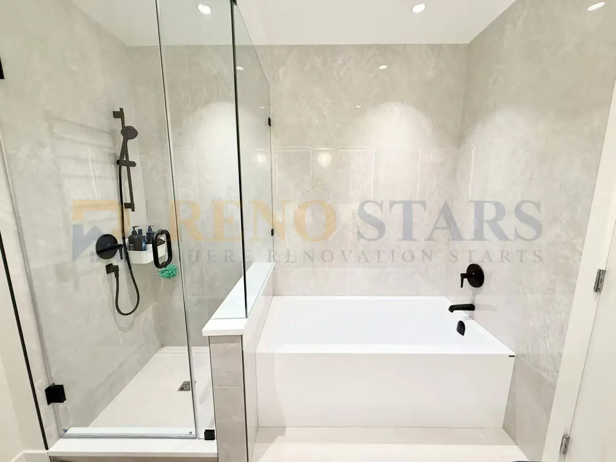 Baño moderno con ducha de vidrio, bañera independiente y herrajes negros elegantes.