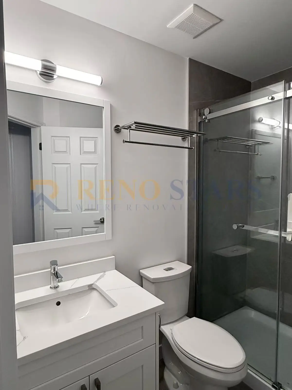 Baño moderno con ducha de vidrio, tocador elegante e iluminación brillante.